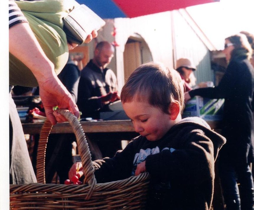 A young shopper puts grapes in the basket at CERES Organic Market